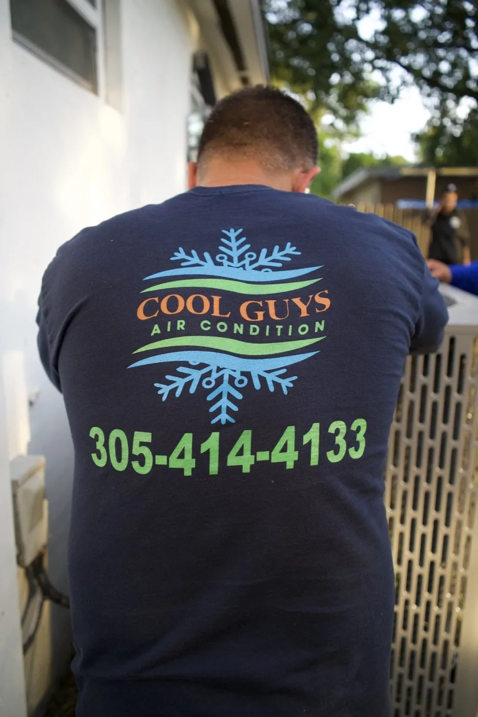 Cool Guys AC technician working on a condenser unit at a South Florida home while Optic Vault films content